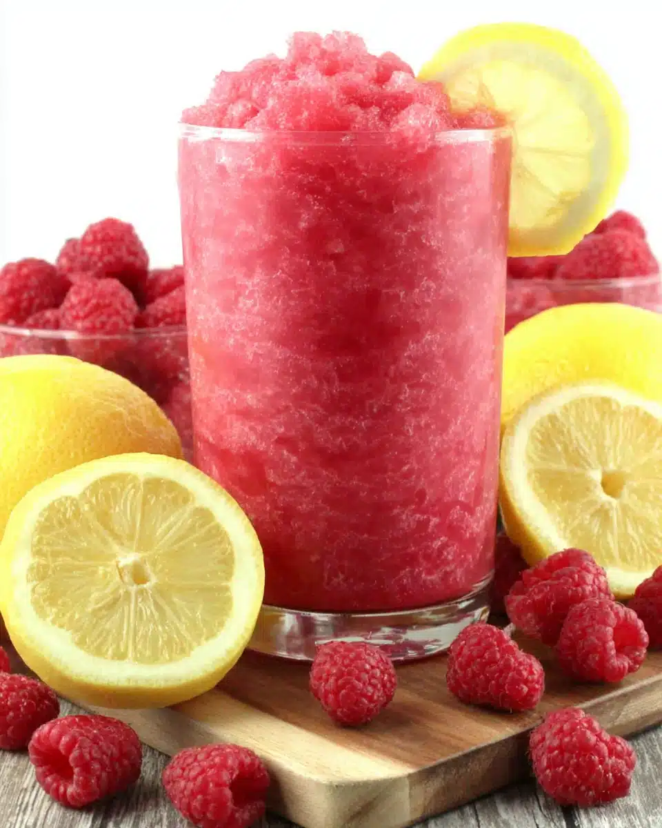 Raspberry Lemonade Slushie Recipe Refreshing raspberry lemonade slushie with lemon garnish and fresh berries