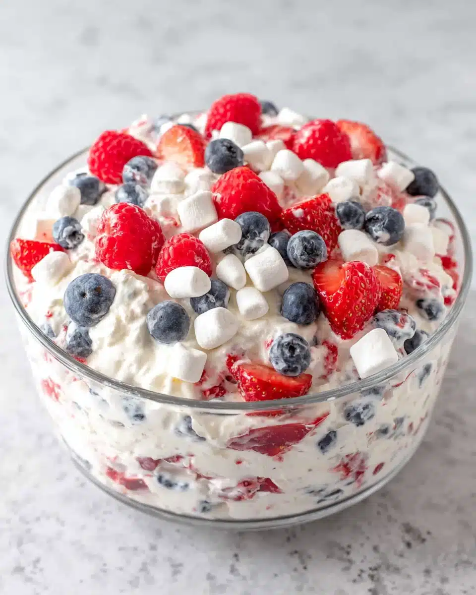 Red white and blue cheesecake salad with fresh berries and marshmallows in a glass bowl