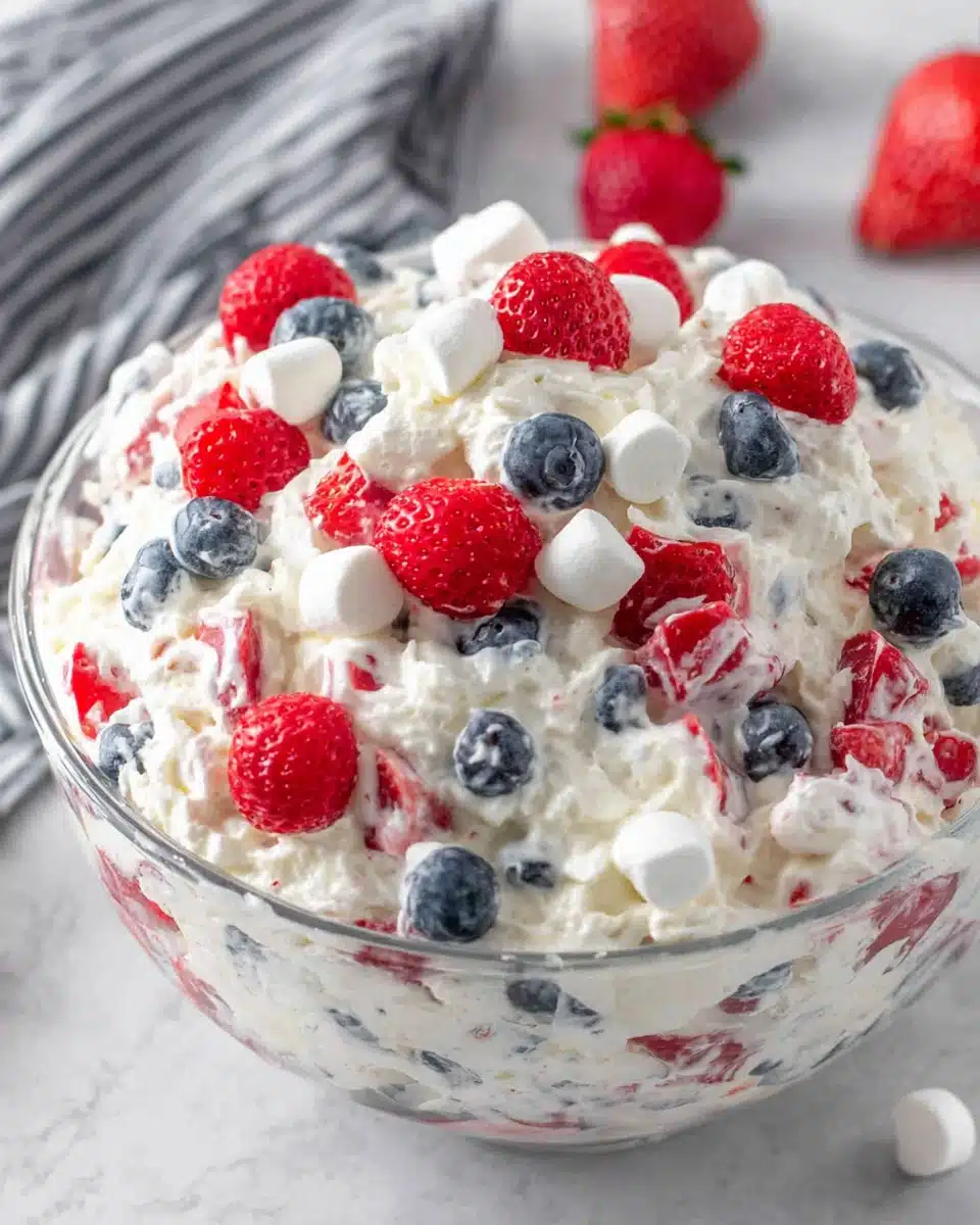 Red white and blue cheesecake salad with fresh berries and marshmallows in a glass bowl