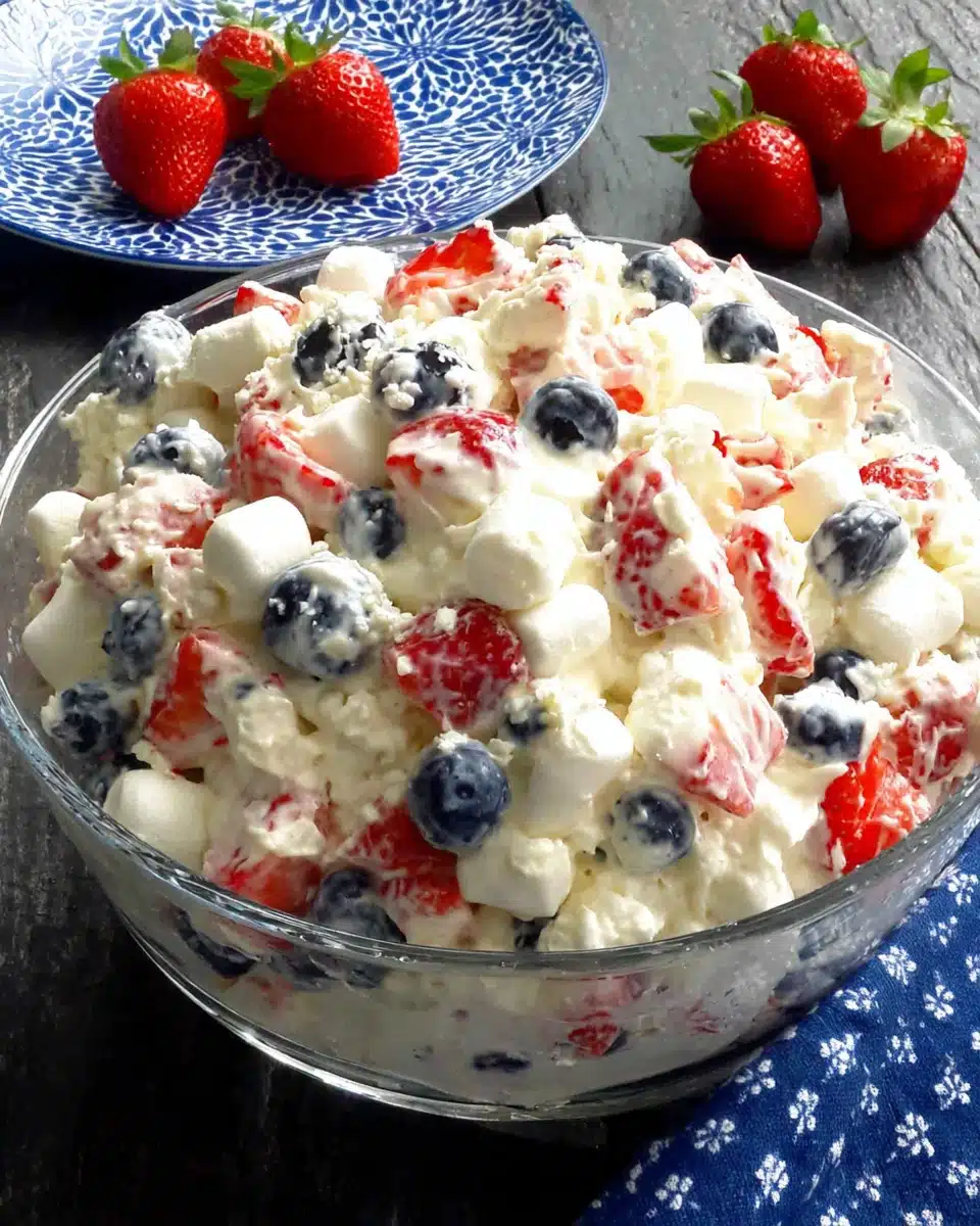 Red, white & blue cheesecake salad with strawberries, blueberries, and marshmallows in a glass dish