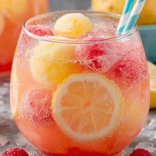 Colorful sherbet punch with rainbow sherbet scoops and fresh fruit in a glass bowl