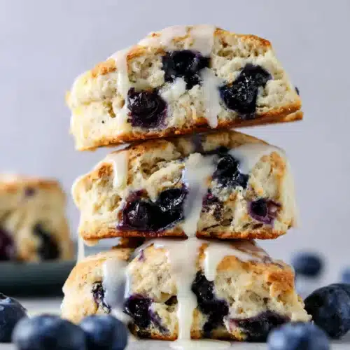 Sourdough blueberry scones stacked with vanilla glaze and fresh blueberries
