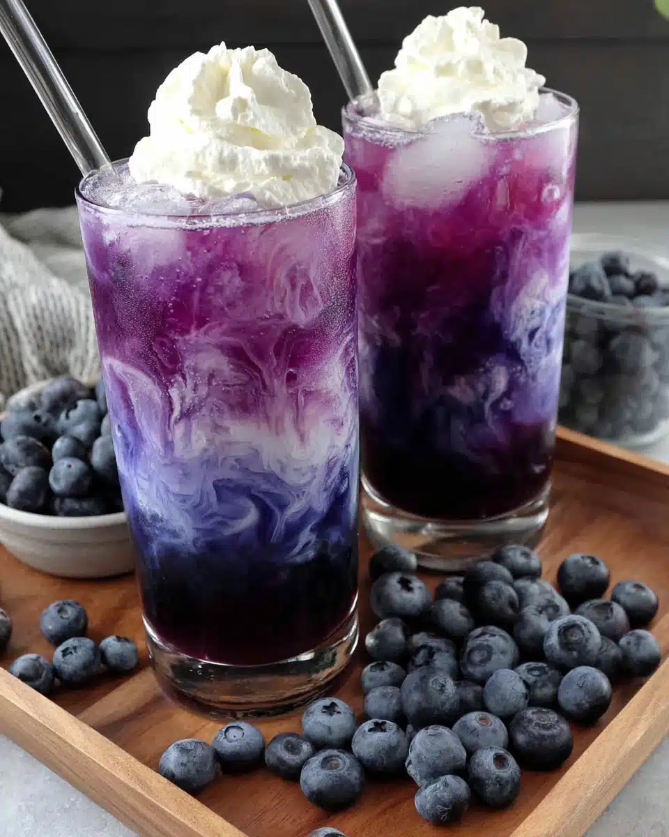 Sugar free blueberry italian cream soda in tall glasses with whipped cream and fresh blueberries