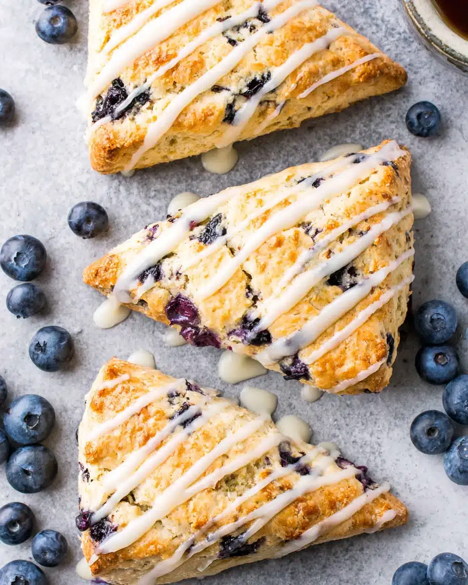 Vegan blueberry scones with white glaze and fresh blueberries on a gray surface