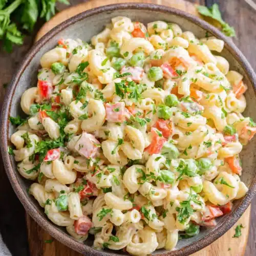 Creamy vegan macaroni salad with fresh vegetables and herbs in a bowl