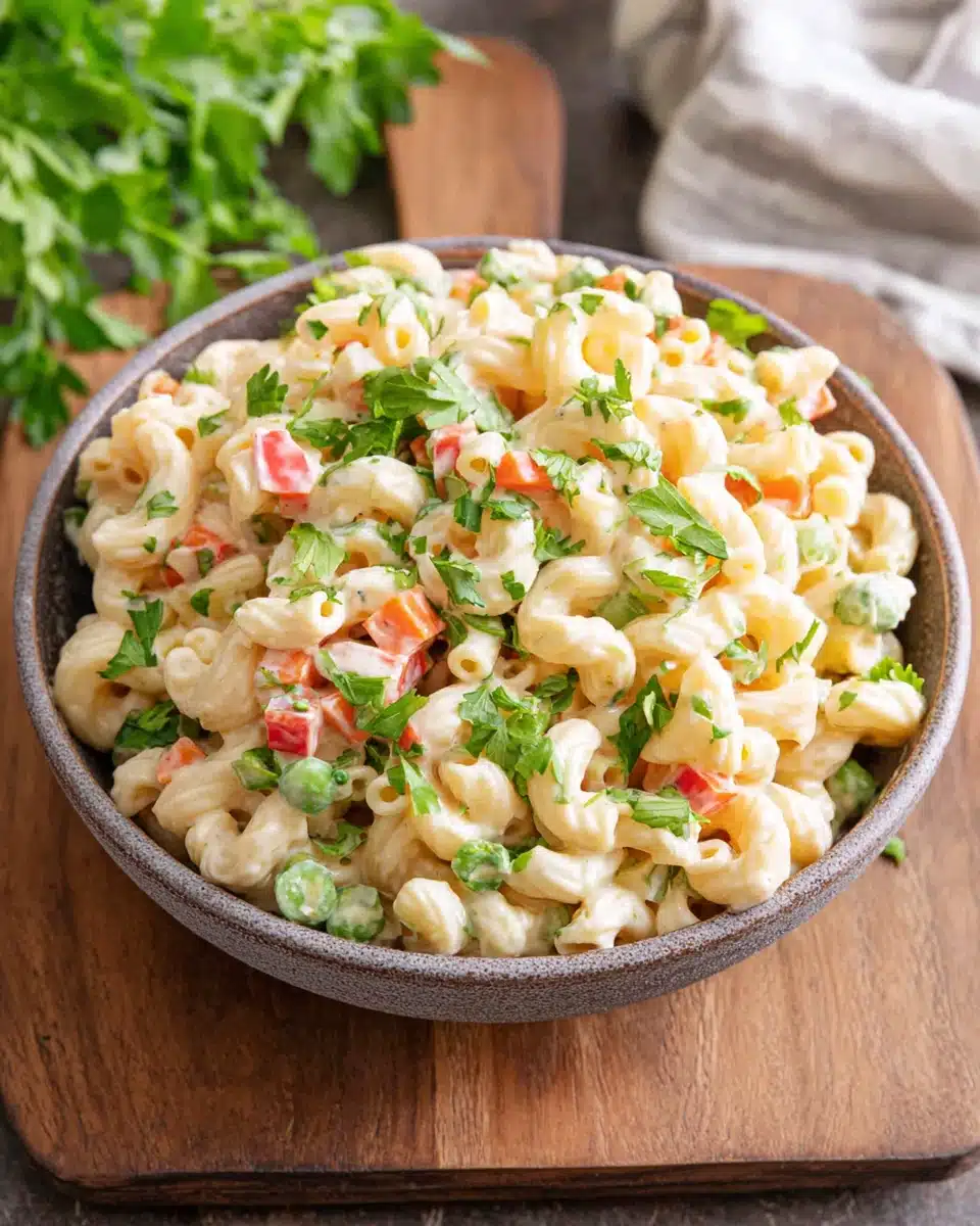 Creamy vegan macaroni salad with fresh vegetables and herbs in a bowl