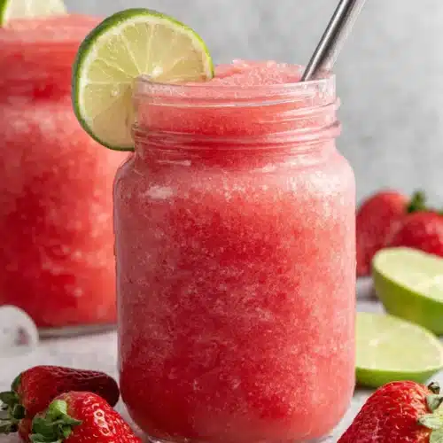 Watermelon and strawberry slushie in a glass jar with lime garnish