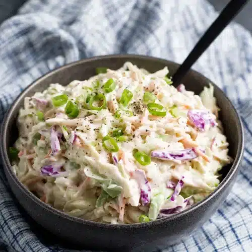 Whole30 Classic Coleslaw: A Simple & Delicious Side 1 Whole30 classic coleslaw in a bowl with green onions and black pepper