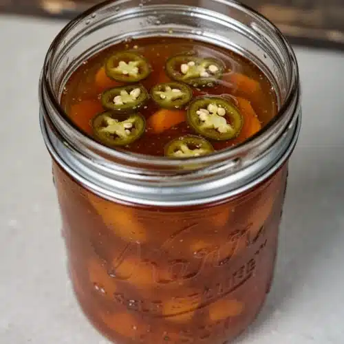 Apricot jalapeno jam in glass jars with silver lids, showcasing rich orange color and chunky texture