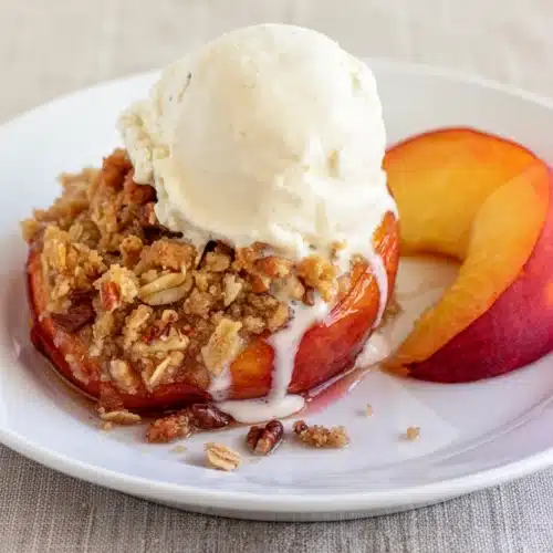 Baked peaches with brown sugar streusel topped with vanilla ice cream