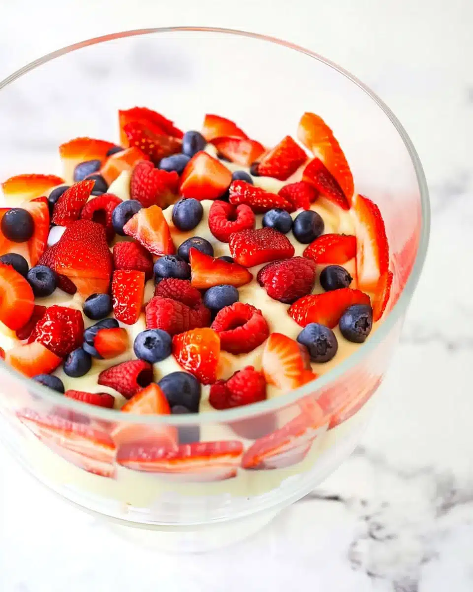 Colorful berry trifle with strawberries, blueberries, and raspberries in a glass bowl