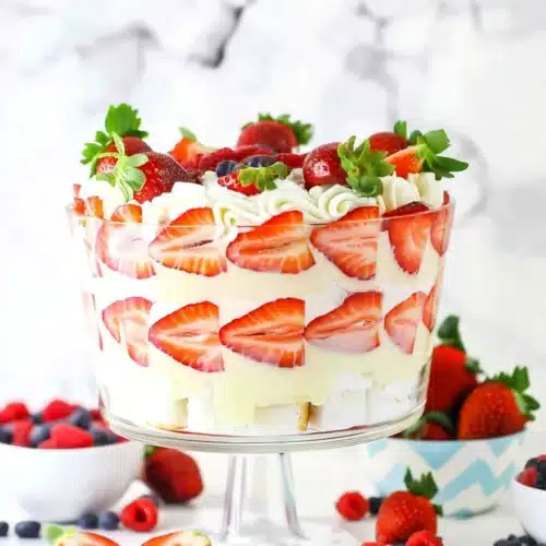 Berry trifle with layers of cake, pudding, and fresh strawberries, blueberries, and raspberries in a glass dish