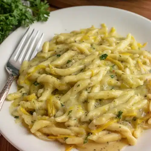 Cheesy Squash Pasta Recipe: A Quick and Delicious Delight 2 Creamy cheesy squash pasta on a white plate with fresh herbs and a fork