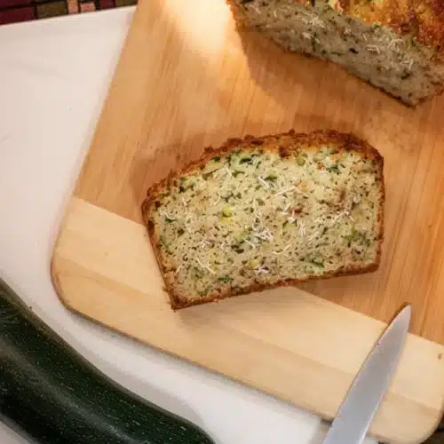 Coconut flour zucchini bread slice on wooden board with fresh zucchini
