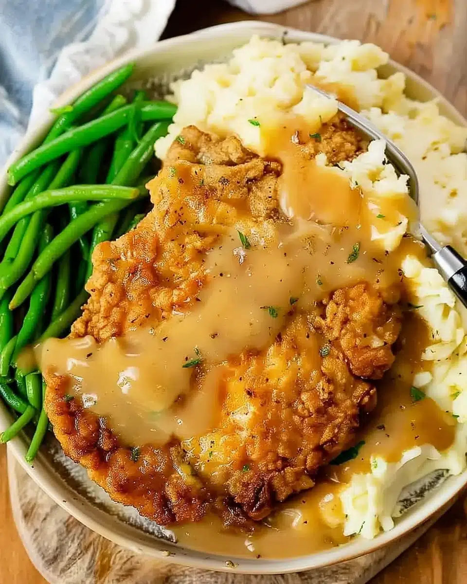 Crispy country fried chicken with gravy, mashed potatoes, and green beans