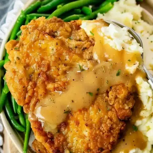 Crispy country fried chicken with gravy, mashed potatoes, and green beans