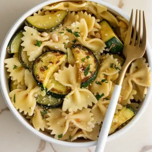 Easy light pasta with zucchini and lemon in a white bowl, garnished with parsley and Parmesan