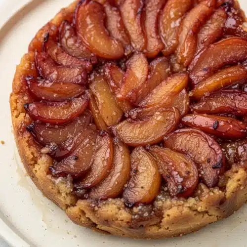 Easy peach tarte tatin with caramelized peaches and golden crust on a white plate