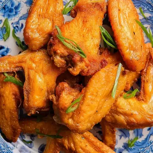 Crispy fried chicken wings (Chinese restaurant style) on a blue and white plate with green onions