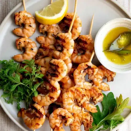 Grilled garlic shrimp skewers with lemon and herbs on a plate