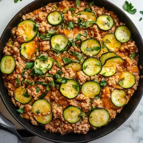 Ground turkey and zucchini skillet with melted cheese and fresh herbs