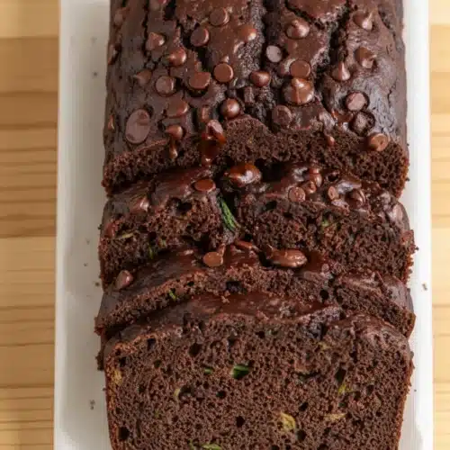 Slices of healthier chocolate zucchini bread with chocolate chips on a white plate