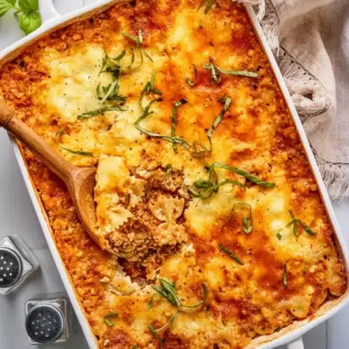 Italian zucchini and ground beef casserole in a white baking dish with melted cheese and basil