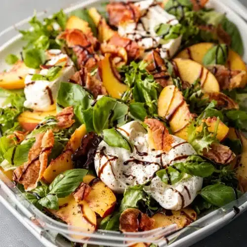 Peach burrata caprese salad with fresh greens, creamy burrata, peaches, and balsamic glaze