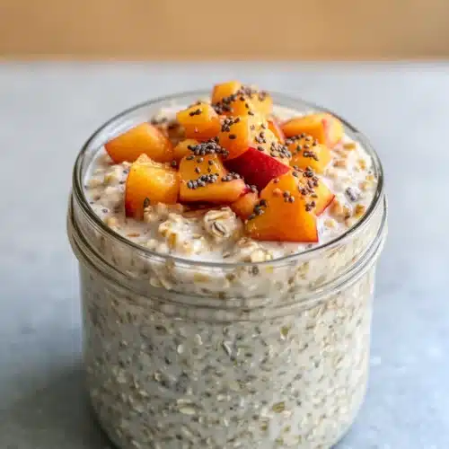 Peach cobbler oats in a jar with fresh peaches and chia seeds