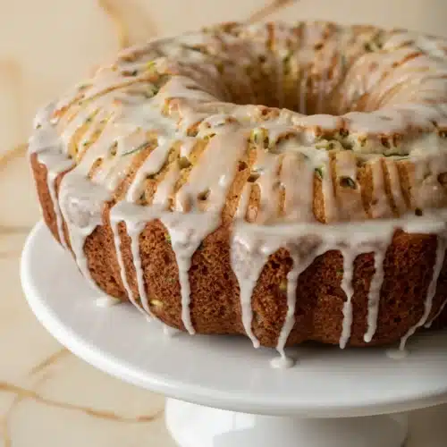 Pineapple zucchini bundt cake with white glaze on a white plate