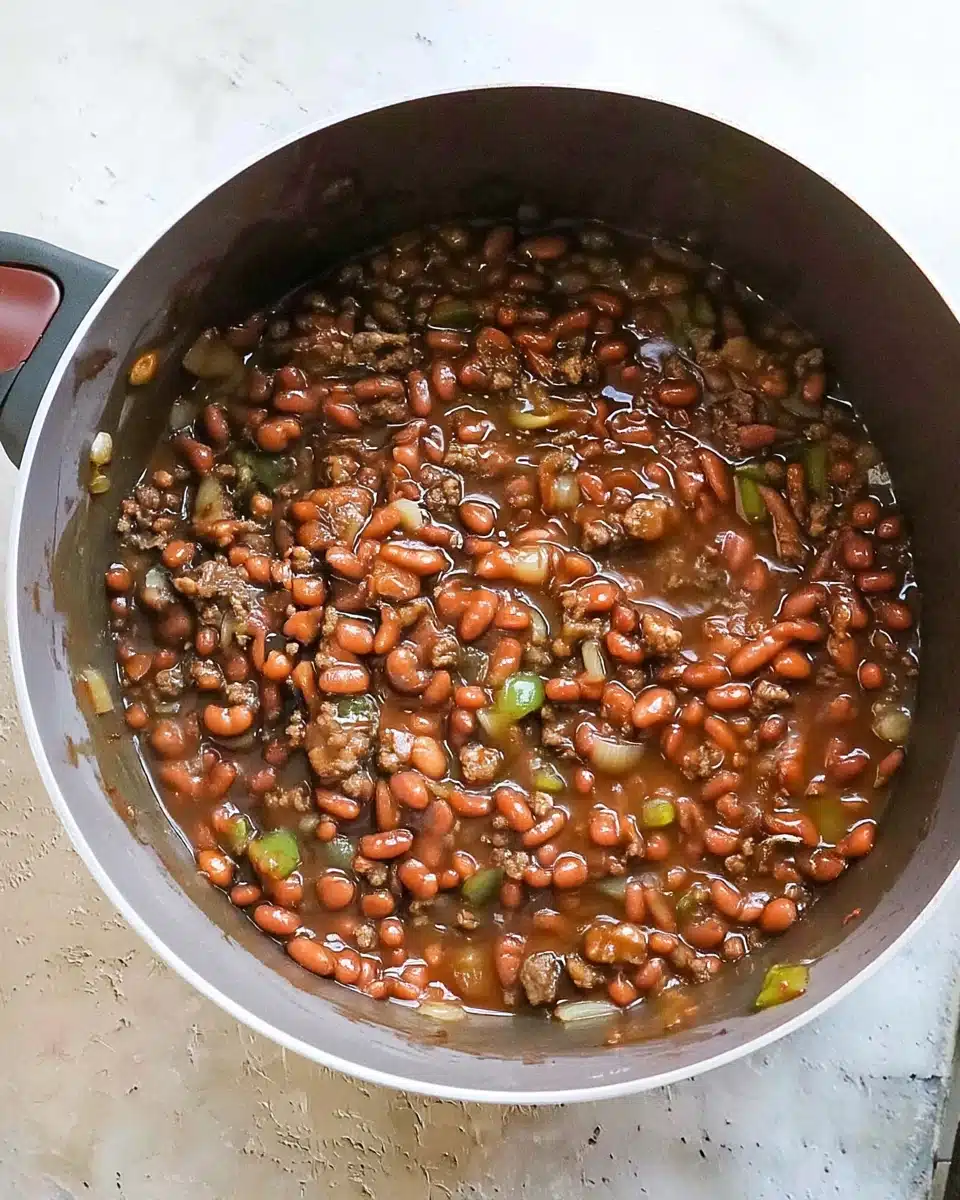 Savory Baked Beans with Ground Beef Recipe Savory baked beans with ground beef in a pot, featuring beans, beef, peppers, and onions.