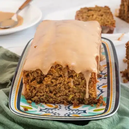 Moist gluten-free zucchini bread with cinnamon cream cheese glaze on a patterned plate