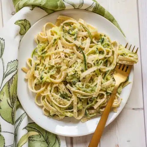 Creamy zucchini alfredo pasta with fettuccine and fresh zucchini ribbons on a white plate