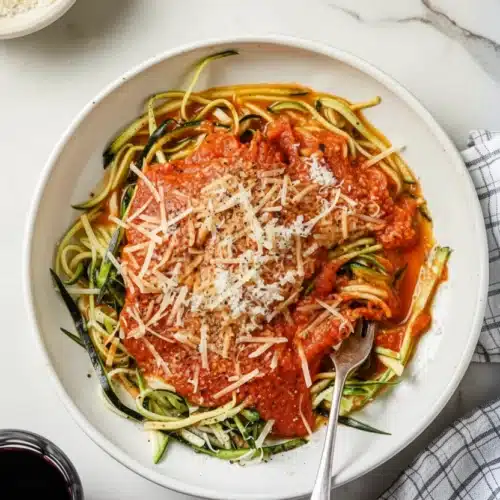 Zucchini noodles with marinara sauce topped with Parmesan cheese