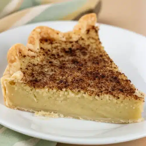 A slice of zucchini pie with a golden crust and cinnamon topping on a white plate