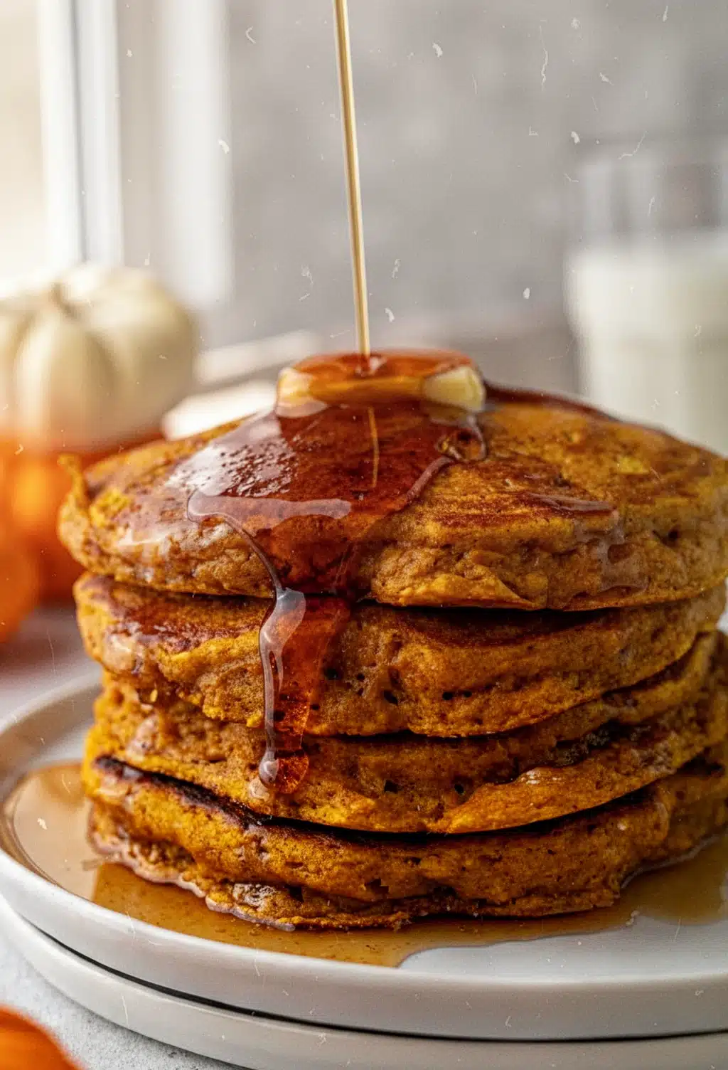 Stack of baked pumpkin pancakes with maple syrup and butter
