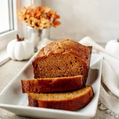 Best Pumpkin Bread Recipe Easy: A Cozy Delight 1 Moist pumpkin bread slices on a white plate with fall decor, best pumpkin bread recipe easy