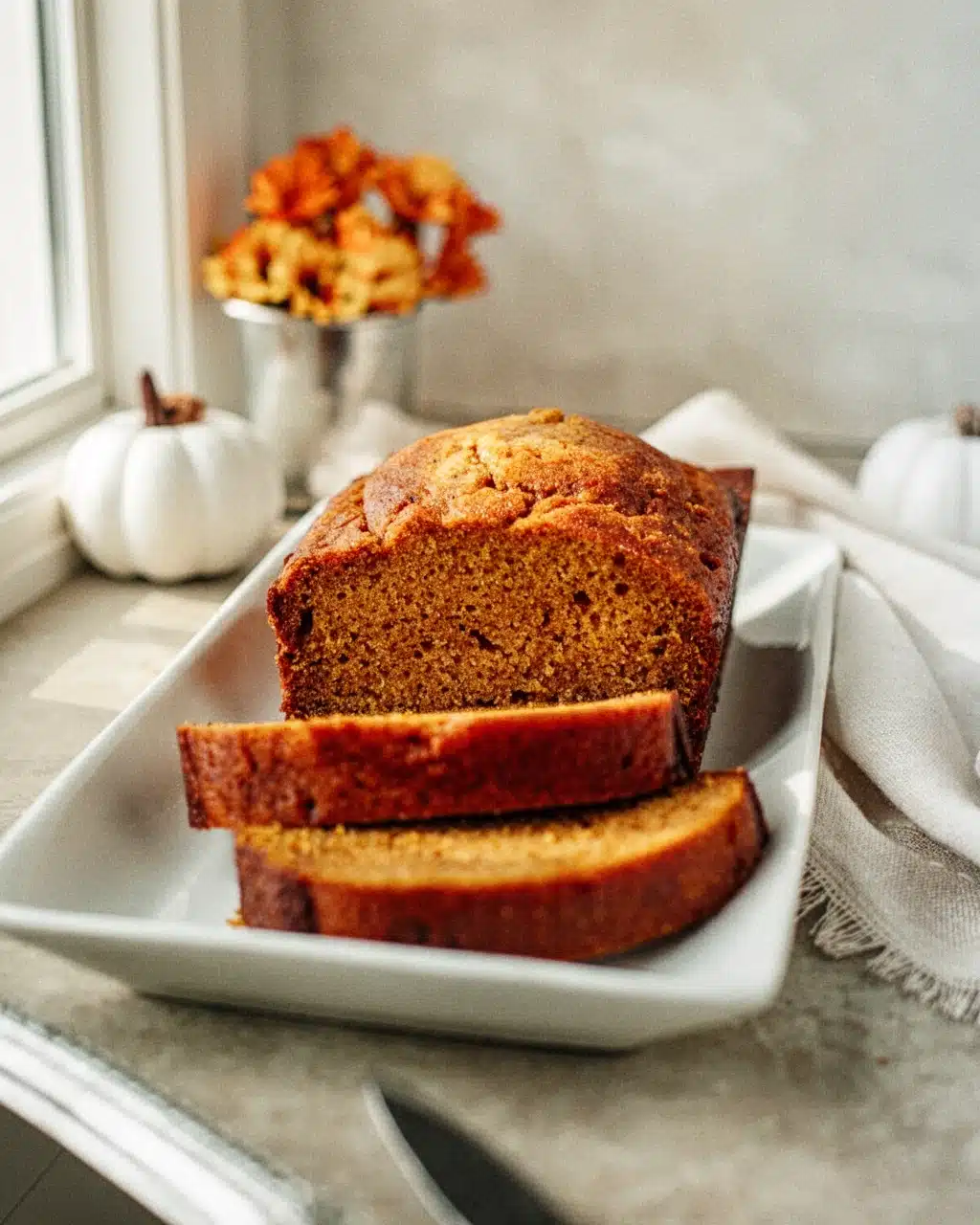 Best Easy Pumpkin Bread Recipe Moist Loaf Slices Moist pumpkin bread slices on white plate with fall decor, best pumpkin bread recipe easy