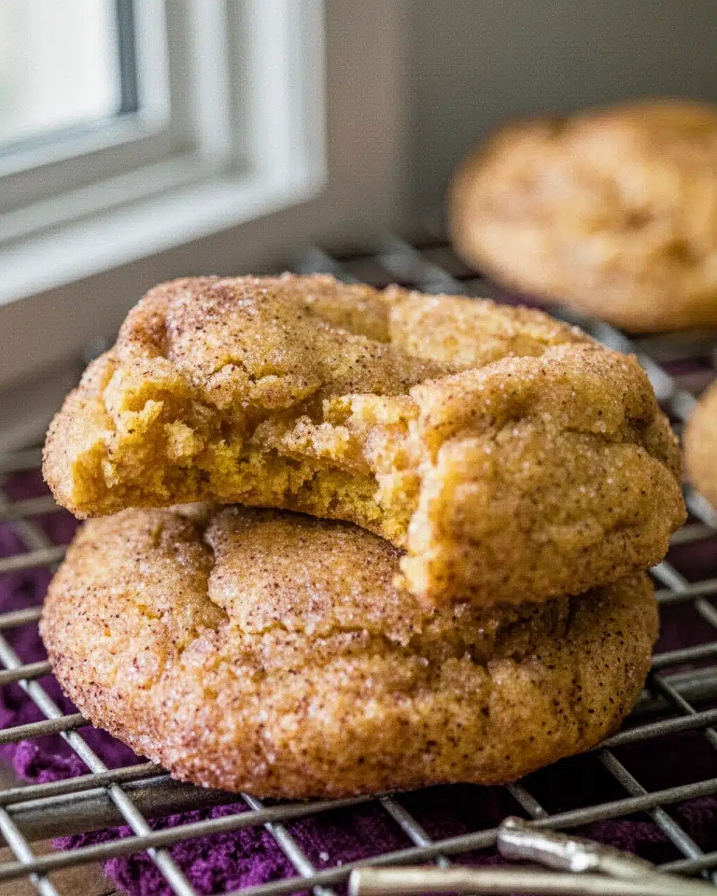 Healthy pumpkin snickerdoodle cookies stacked on a cooling rack, golden and chewy