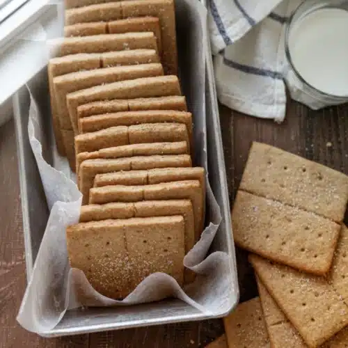 Delicious Graham Cracker Recipe You’ll Adore 1 Homemade graham crackers in a loaf pan with milk and a striped towel